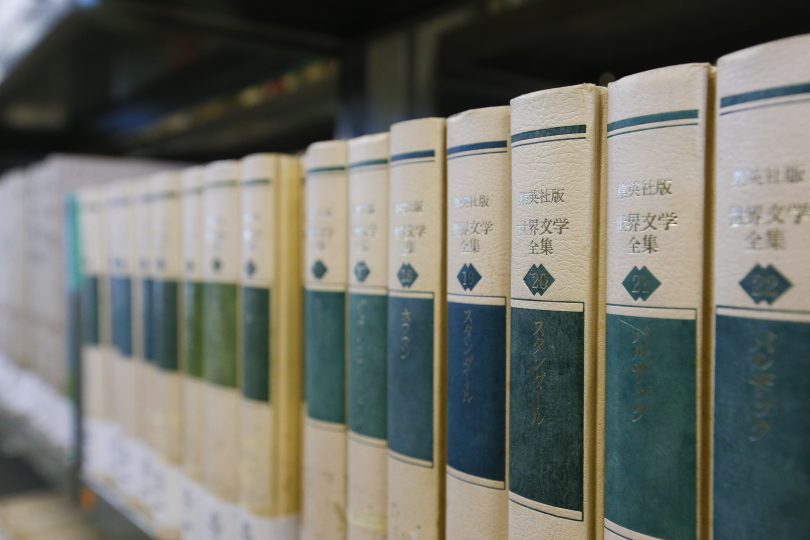 Foto com diversos livros em cor bege com escritas em japonês que se traduzem como "coletânea de literatura mundial'